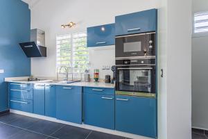 a blue kitchen with blue cabinets and a microwave at Villa Plumbago in Sainte-Anne