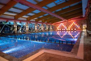 a large swimming pool with lights in a building at Hotel Borovi Forest Resort & Spa in Sjenica