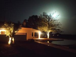 uma casa iluminada à noite com árvores em frente em Quinta Marugo Retreats em Serpa
