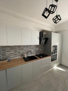 - une cuisine avec des placards blancs et un évier dans l'établissement City View Apartment, à Constanţa