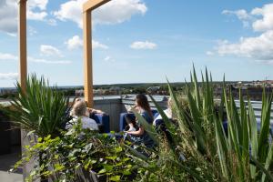 a group of people sitting on top of a building with plants at ProfilHotels Halmstad Plaza in Halmstad
