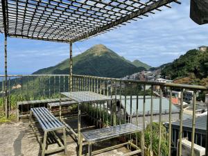 una mesa y bancos en un balcón con una montaña en Linyuan Village, en Jiufen