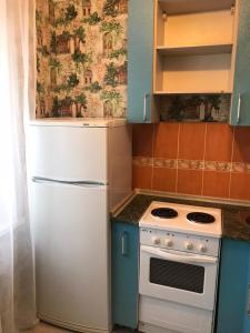 a kitchen with a white stove and a refrigerator at Lux Home на Амурской in Ustʼ-Kamenogorsk