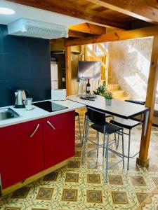 ラスパルマス・デ・グランカナリアにあるVacacionales Veguetaのキッチン(赤いキャビネット、テーブル、椅子付)