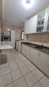uma cozinha com armários brancos e piso em azulejo em Otimo apartamento em Balneário Camboriu em Balneário Camboriú