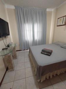 1 dormitorio con 1 cama con mesa de cristal y TV en Otimo apartamento em Balneário Camboriu, en Balneário Camboriú