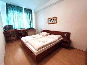 Schlafzimmer mit einem Bett, einem Schreibtisch und einem Fenster in der Unterkunft HOTEL JURKI Dom in Bratislava