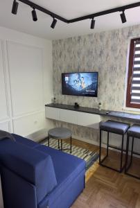sala de estar con sofá azul y TV en Jahorina Apartman Benvenuti en Jahorina