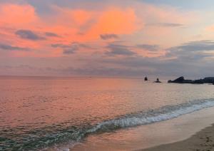 a sunset over the ocean with a sandy beach at 4U Resort Samui in Lamai