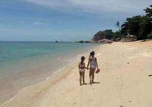 two girls standing on a beach near the water at 4U Resort Samui in Lamai