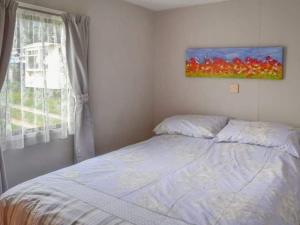 BactonにあるNorfolk Poppy Caravan - Sleeps 4 - WiFi and Sky TV Includedのベッドルーム1室(ベッド1台付)が備わります。壁には絵画が飾られています。