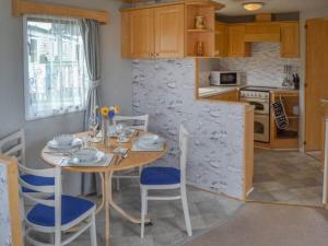 a kitchen with a table and chairs in a kitchen at Norfolk Poppy Caravan - Sleeps 4 - WiFi and Sky TV Included in Bacton