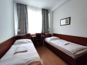 Habitación con 2 camas, mesa y ventana en HOTEL JURKI Dom en Bratislava