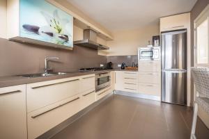 a kitchen with white cabinets and a stainless steel refrigerator at Chalet Cortijo Blanco I in Marbella