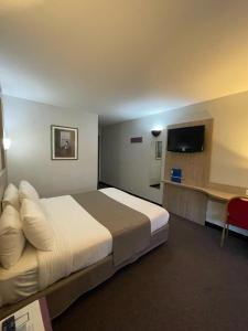 a hotel room with a large bed and a television at Kyriad Saint Fargeau Ponthierry - Apollonia in Saint-Fargeau-Ponthierry