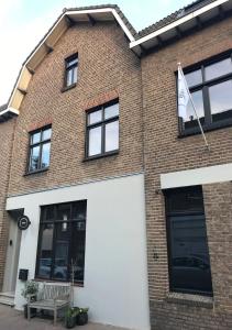 a brick building with a white garage door and a flag at B&B De Oude Dorpsslagerij in Nuth