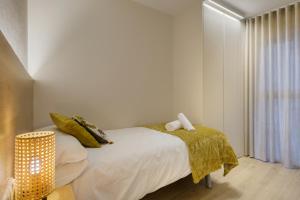 1 dormitorio con 1 cama con sábanas blancas y almohadas amarillas en Apartamentos La muralla de Jaca, en Jaca