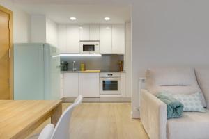 a kitchen with white cabinets and a chair and a table at Apartamentos La muralla de Jaca in Jaca