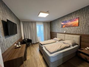 een slaapkamer met een bed, een bureau en een televisie bij F Hotel in Hörsching