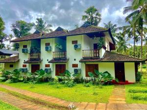 a white house with a balcony and palm trees at Kalappura Farm House Heritage in Ottappālam