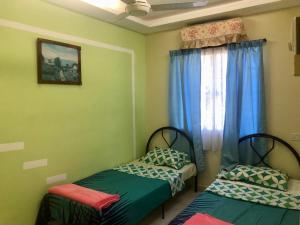 2 camas individuales en una habitación con ventana en Ipoh Tambun Cozy & comfortable, en Kampong Batu Lapan