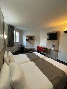 une chambre d'hôtel avec un grand lit blanc et des chaises dans l'établissement Kyriad Saint Fargeau Ponthierry - Apollonia, à Saint-Fargeau-Ponthierry