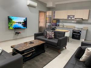 a living room with two couches and a kitchen at Queens View Apartment in Accra