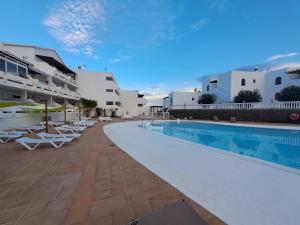 een zwembad naast een gebouw met witte gebouwen bij Comfortable Cleo apartment with large terrace in Costa Teguise