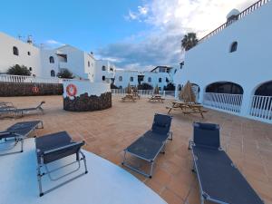 een patio met stoelen en tafels en witte gebouwen bij Comfortable Cleo apartment with large terrace in Costa Teguise