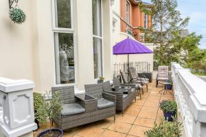 een patio met rieten stoelen en tafels in een gebouw bij The Netley in Torquay