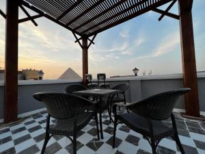 uma mesa e cadeiras num telhado com vista para as pirâmides em Pyramids Gate Hotel no Cairo