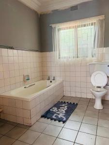 een badkamer met een bad en een toilet bij Ezrom Bright Holiday Home in Port Shepstone