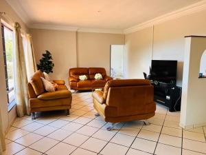 - un salon avec des fauteuils en cuir et une télévision dans l'établissement Ezrom Bright Holiday Home, à Port Shepstone