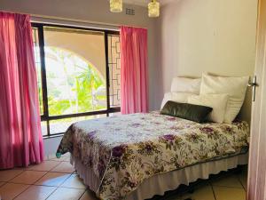 - une chambre avec un lit doté de rideaux roses et d'une fenêtre dans l'établissement Ezrom Bright Holiday Home, à Port Shepstone