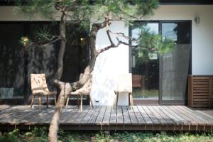 two chairs and a tree on a wooden deck at AMIGO HOUSE in Zushi
