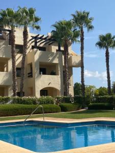 een gebouw met palmbomen voor een zwembad bij Penthouse Casa Baja las Palmeras - Roda Golf in San Javier