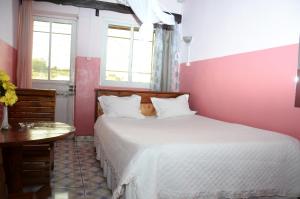 ein Schlafzimmer mit einem weißen Bett, einem Tisch und einem Fenster in der Unterkunft Rem Hotel in Fianarantsoa