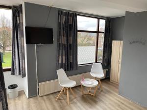 a living room with two chairs and a tv at Hotel Cafe The Windmill in Schiedam