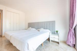 Dormitorio blanco con cama blanca y cortina púrpura en Apartamento Dúplex Los Cartujanos I, en Marbella