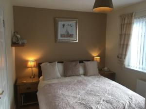 a bedroom with a white bed with two lamps and a window at Silverstrands in Inverness