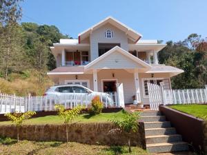 a house with a white fence and a car at Green Valley Vista in Munnar