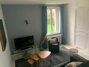 a living room with a couch and a tv and a chair at Sous le grand Cèdre in Le Quesnoy-en-Santerre