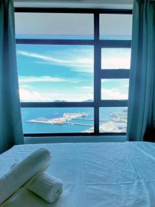 a bedroom with a large window with a view of the ocean at Jesselton Quay by Bunga Raya Homes in Kota Kinabalu