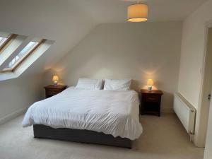 um quarto com uma cama branca com duas mesas de cabeceira em Modern 5 bedroom house in Spanish Point Clare em Spanish Point