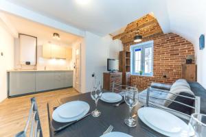 a dining room with a table and a brick wall at Hello Apartments Sw Ducha Loft for 4 guests in Gdańsk