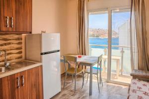 a kitchen with a refrigerator and a table with a window at Despinas Seafront Apartments,Haraki in Haraki