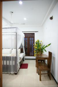 a bedroom with a bed and a table and a window at Villa Sunimal in Unawatuna