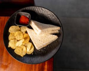 a plate of crackers and chips on a plate with a snack at Lotus Feet Cottages, 100 Odd Meters from Morjim Beach in Morjim