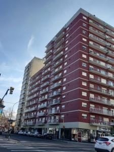 un edificio rojo alto con coches estacionados frente a él en DEPTO CENTRO EN MAR DEL PLATA 4 PERSONAS (hasta 5 se puede conversar) en Mar del Plata