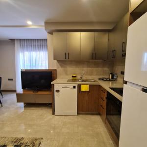 a kitchen with a white refrigerator and a tv at BİSUİTES in Antalya